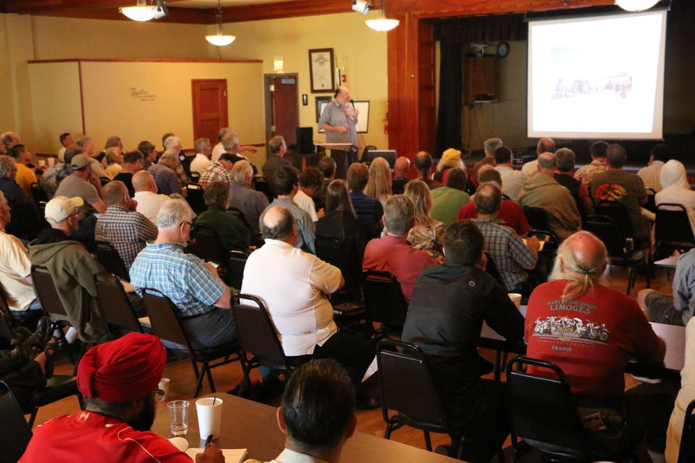 A full room at the 2015 Energy Science & Technology Conference, a presenter at the front beside the projection screen